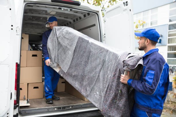 two young delivery men in uniform unloading furniture from vehicle