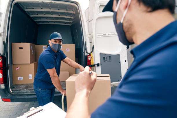 two couriers in protective face masks unloading packages