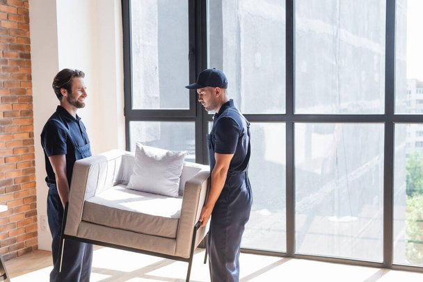 stock photo movers uniform holding white armchair